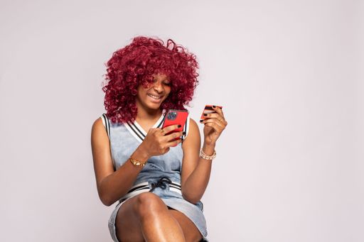 happy african lady using her phone and credit card