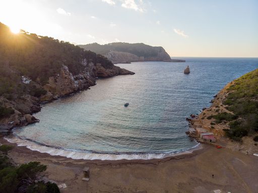 a beautiful view of a beach surrounded by mountains at sunset