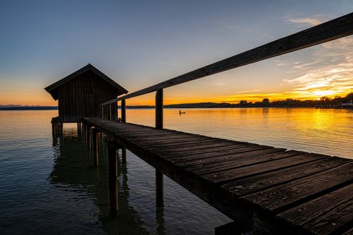 A wooden boat house at a lake in Southern Germany at sunset