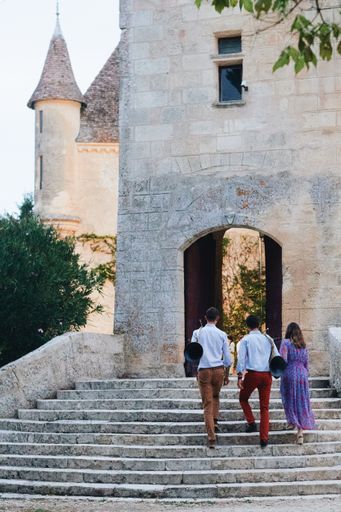 A vertical shot of people on stairs leading to an old castle in France