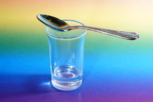 A closeup shot of a spoon on a glass on a colorful background