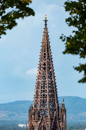 A vertical shot of the Freiburger Munster cathedral against a blue sky.