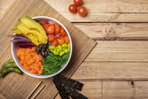 Poke bowl with salmon, avocado, tomato and seaweed. Top view