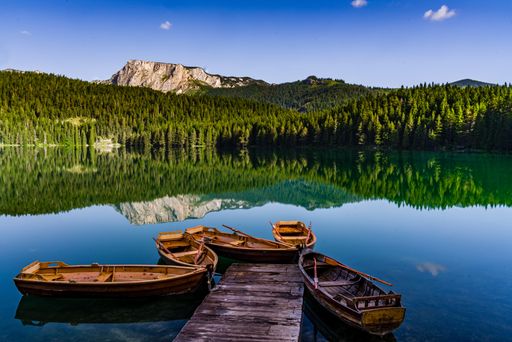 A shot of a Black lake with the focus of boats with the Dormitory mountain background in Montenegro