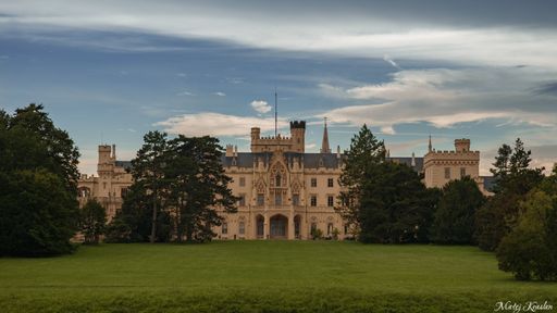 Panoramatic shot of Lednice castle with blue clouded sky and nature around it