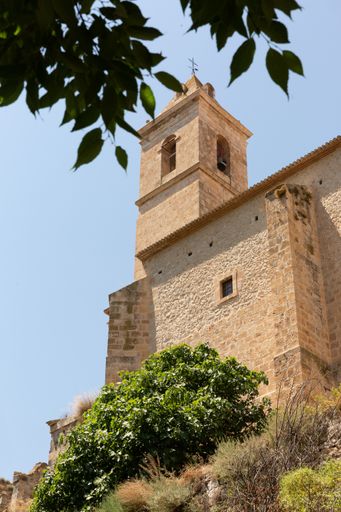A low angle shot of a castle located on top of the hill in Alcala del Jucar against a cloudless sky