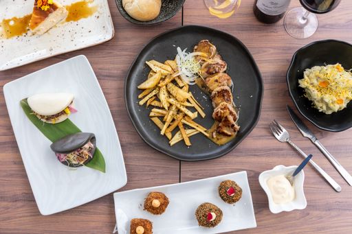 A top view of a variety of delicious dishes and cutlery on a wooden restaurant table