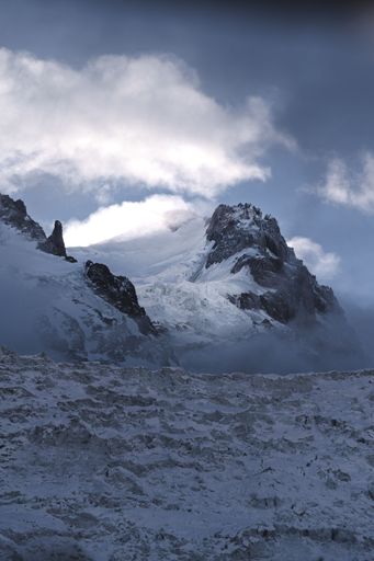A vertical shot of snowy mountains in the clouds
