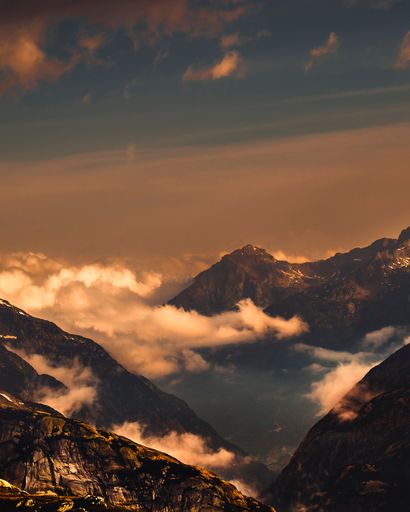 A vertical shot of mountain peaks on a gloomy day during sunset