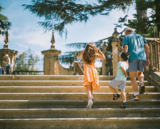An old man with his grandchildren climbing the stairs. Coimbra, Portugal.