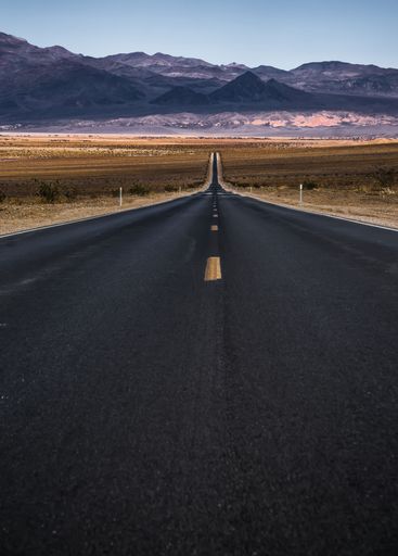 A scenic view of a long winding road against a backdrop of majestic mountains