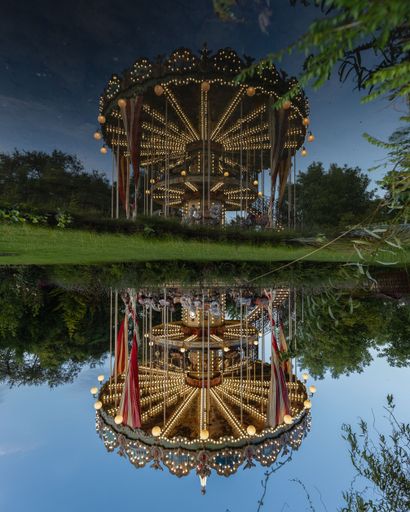 A vertical shot of a carousel reflected in the water in Fairy Garden, Miskolc, Hungary