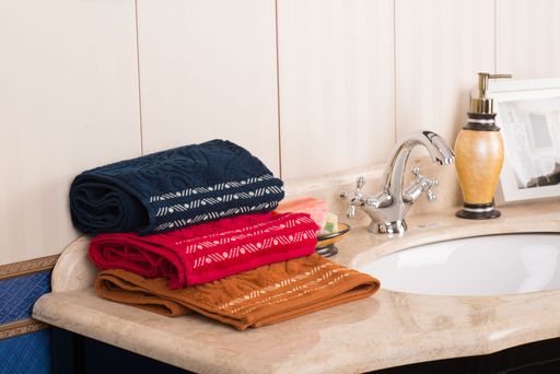 A closeup shot of folded colorful bamboo towels on a decorative bathroom cabinet with a sink