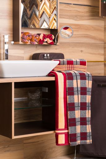 A vertical shot of a hanging plaid towel on a bathroom cabinet near a sink