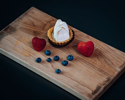 A mini pie, strawberries, and blueberries on a wooden cutting board