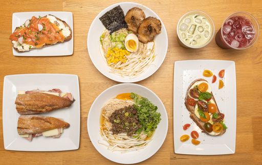 A top view of different meals with ramen, lemonades, and sandwiches on the kitchen table