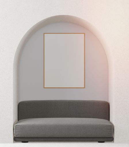 An interior living space with a grey couch, arch and blank painting, with copy space