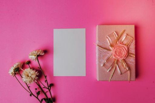 A pink background with a blank white card and fresh yellow flowers, with copy space