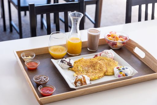 A closeup shot of a food tray filled with different foods and drinks placed on a wooden table