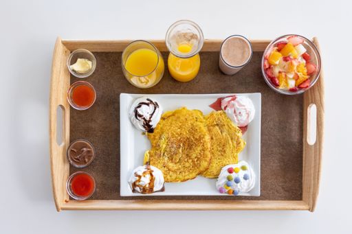 A top view of a food tray filled with different foods and drinks placed on a wooden table