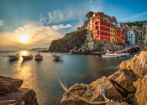 A Beautiful sunset over a colorful village on a cliff with boats in the sea below