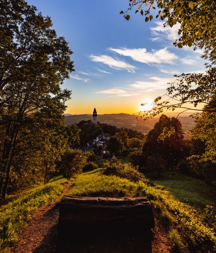 A view over the city from the park on top of the hill with a wooden log as a seat during sunset
