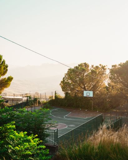 A vertical distant view of a basketball court during sunset