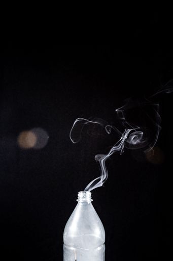 The smoke coming out of a plastic bottle on black background -  aromatherapy concept