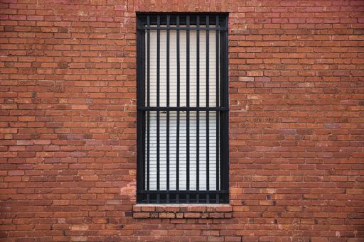 A window with black metal bars on a brick building