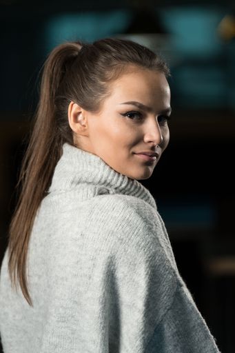 A vertical closeup of a beautiful young woman looking at the camera.