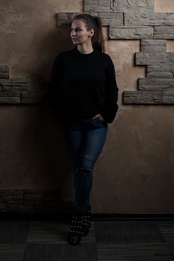 A vertical Portrait of Pretty Young Woman Standing Against Brick Wall