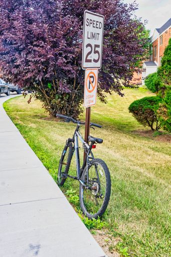 A vertical shot of a speed limit sign with bike chained to it