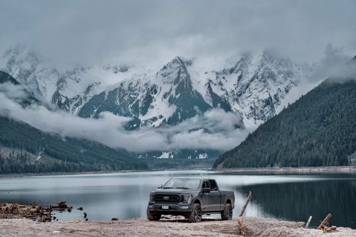 A Ford F150 car parked at the lake on the background of breathtaking snowy mountains