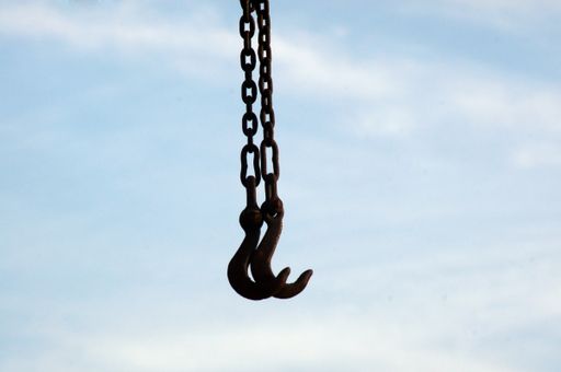 A closeup of the chain and cable hoist of a crane under the sunlight