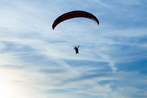 A cloudy blue sky with a silhouette of a paraglider