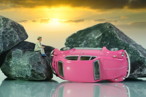 a man sits on a rock after a car accident , white background, sunset sky, miniature figures toys scene, concept: good insurance is important
