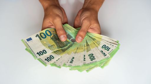 A hand holding a pile of 100 euro banknotes on a white background