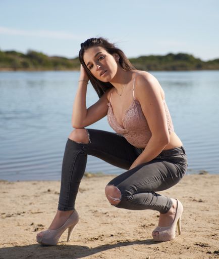 A vertical shot of a beautiful young woman posing on the beach