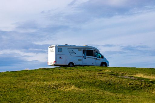 A motorhome on the top of a hill under the blue cloudy sky