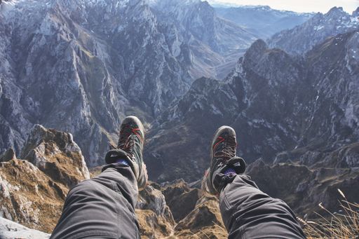 A closeup of a hiker's feet while sitting in front of the beautiful scenery of mountains in Asturias, Spain