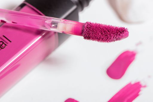 A closeup shot of pink shade liquid lipstick wand isolated on white background with swatches