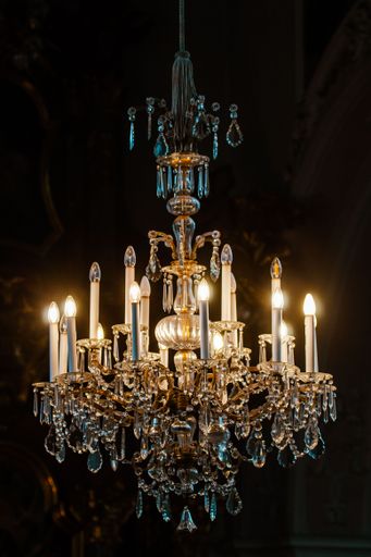 A vertical shot of a luxurious vintage chandelier with beautifully shaped glass decorations and yellow lights