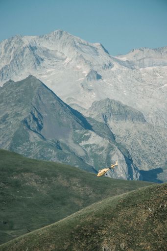 A drone vertical shot of helicopter hovering over mountain in the morning