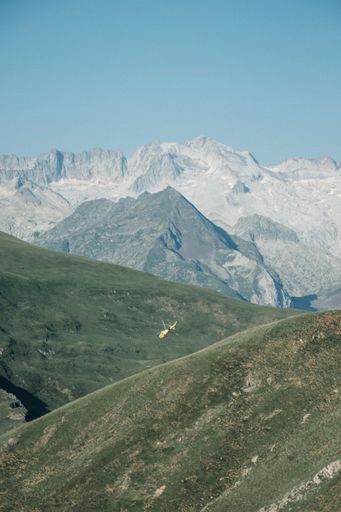 A drone vertical shot of helicopter hovering over mountain in the morning
