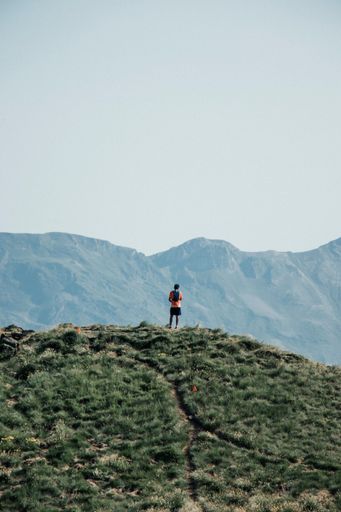 A drone vertical shot of a man on a mountain against the sky in the morning