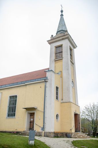 A vertical of an old church from a garden under the cloudy sky