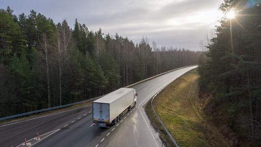 An aerial view on the Via Baltica highway with driving vehicles crossing the pine forest dunes in Luitemaa nature reserve