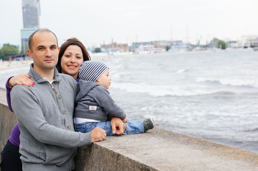 Woman, man and a child standing by a wall close by the sea.