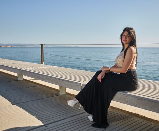 A Caucasian woman wearing an evening dress and posing near the sea