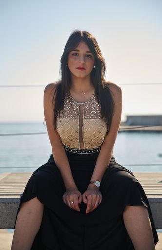 A vertical shot of a Caucasian woman wearing en evening dress and posing